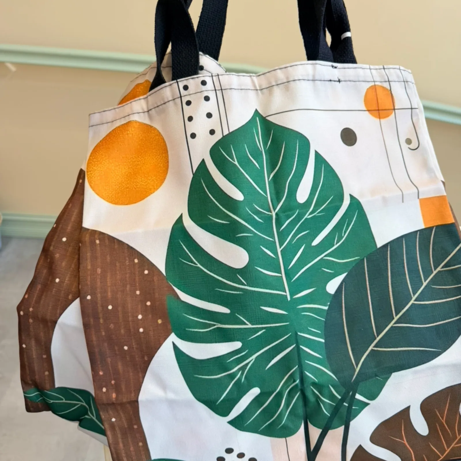 Monstera Leaf Tote bag with green leaves, oranges, and brown botanical print design.