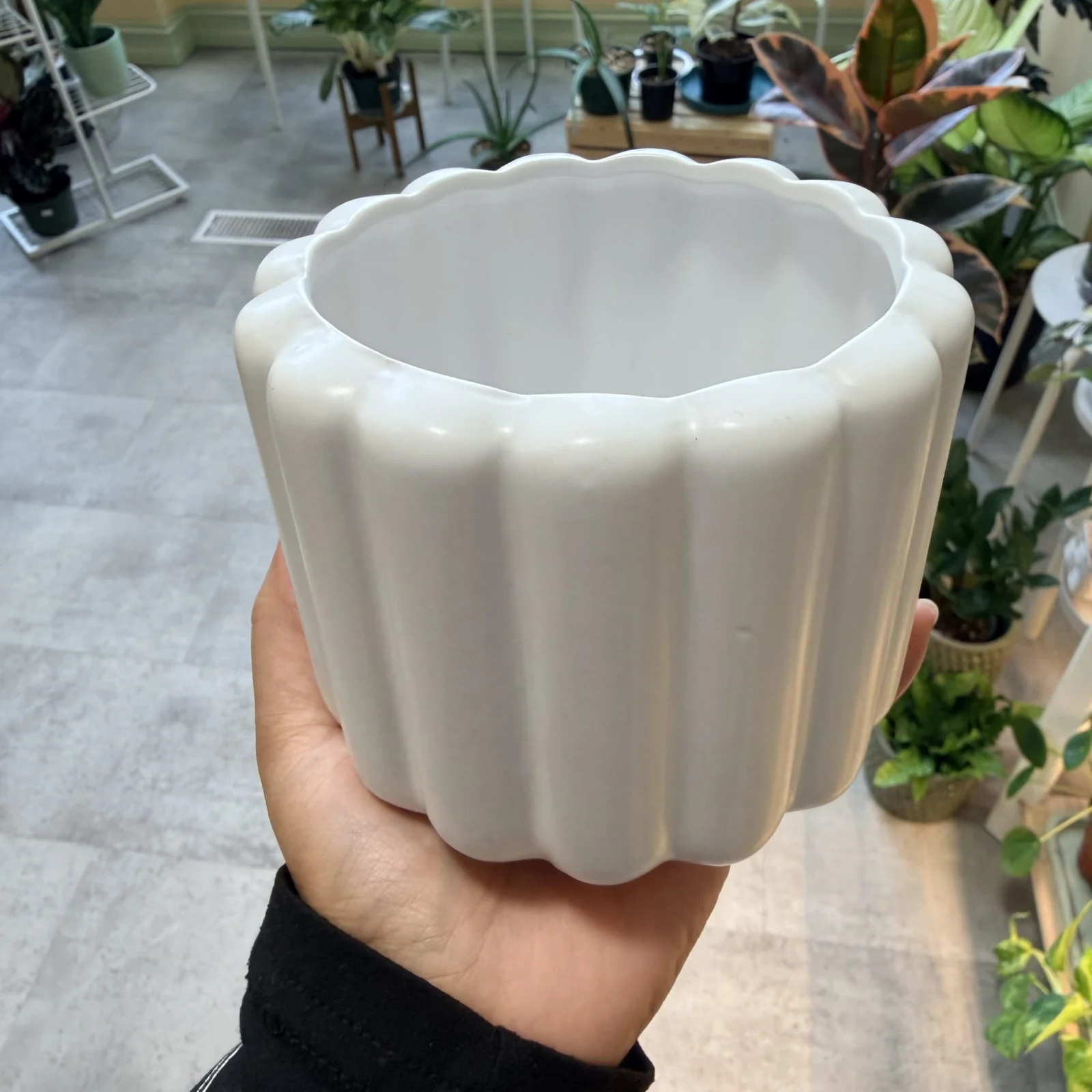 4" Beau Pot Round white ceramic fluted planter pot held in hand, empty.