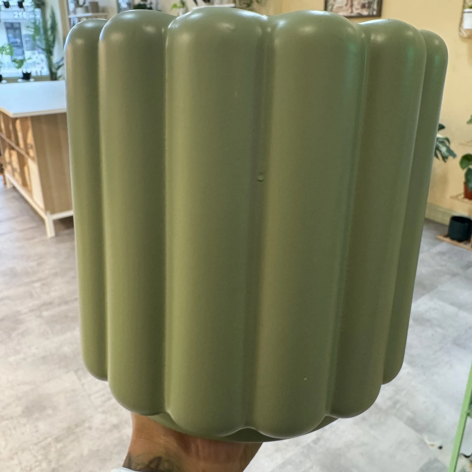 Green Fluted Ceramic Pot with vertical ridged design, held in hand, indoors.