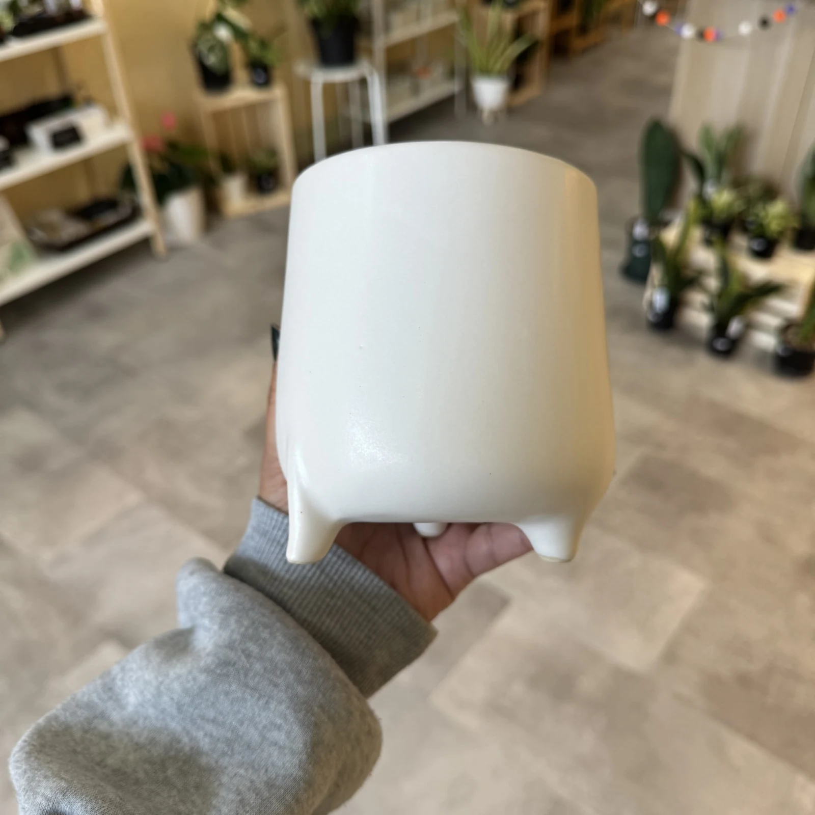 White Pot with Feet held in hand, minimalist ceramic planter design.