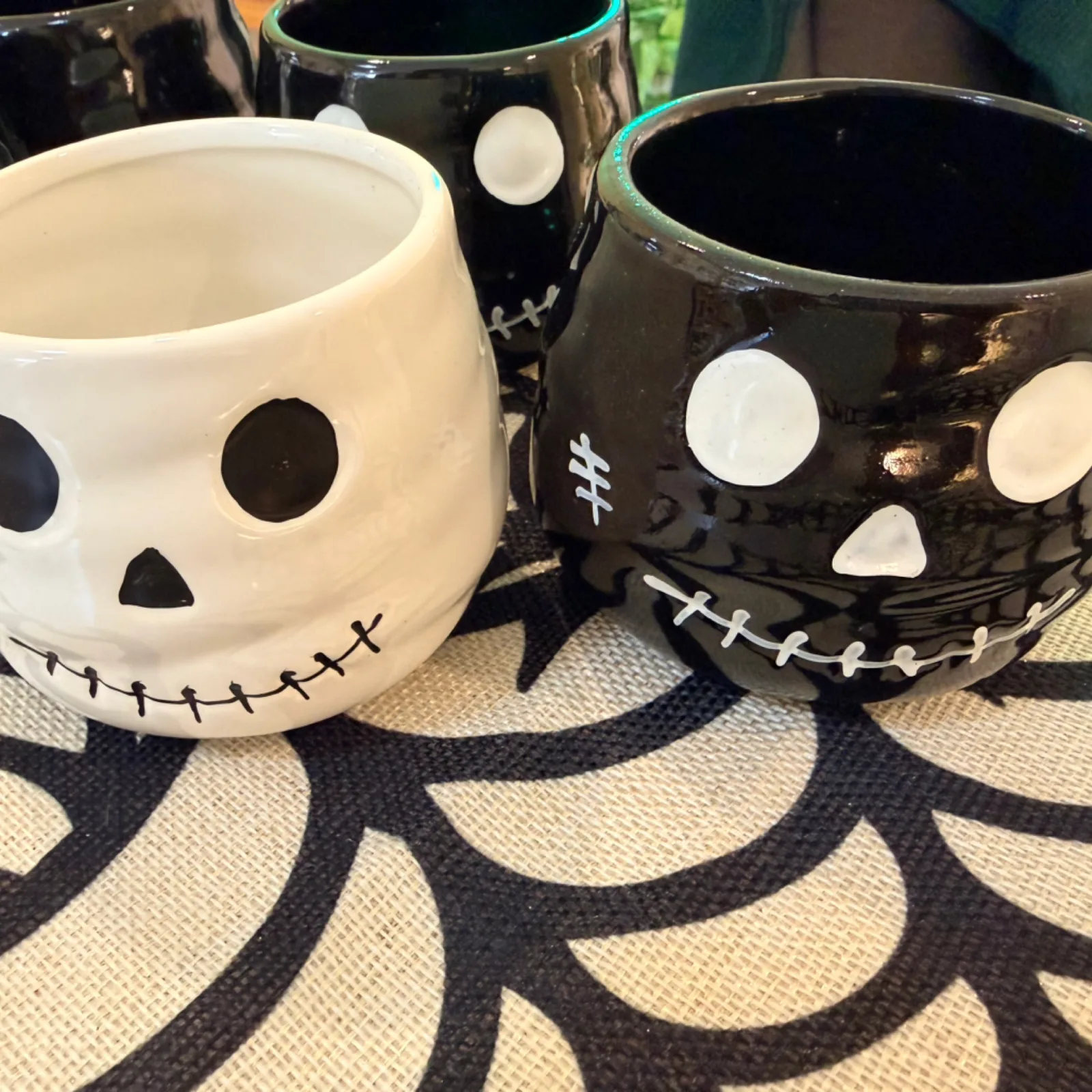 Halloween Faces ceramic mugs with stitched smile design on spider web placemat.