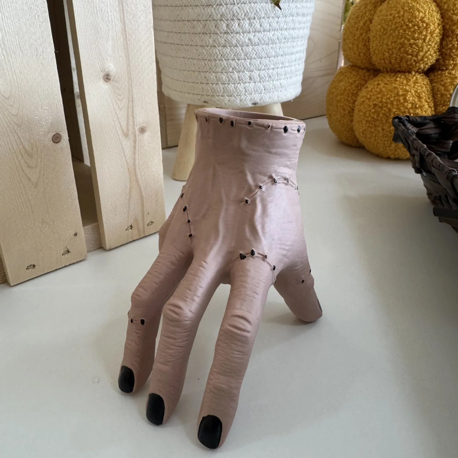 Thing Hand Plant Pot with pale pink ceramic hand-shaped planter holding small dark succulent.