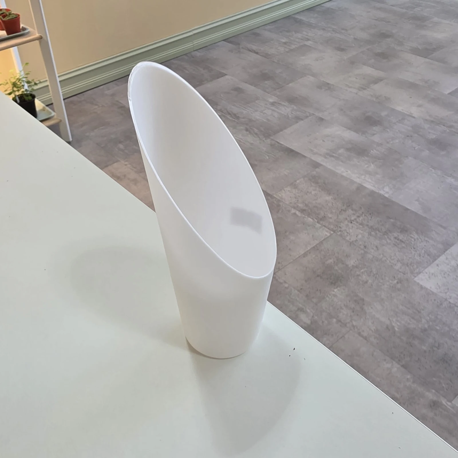 White ceramic substrate scoop sitting on white surface indoors.