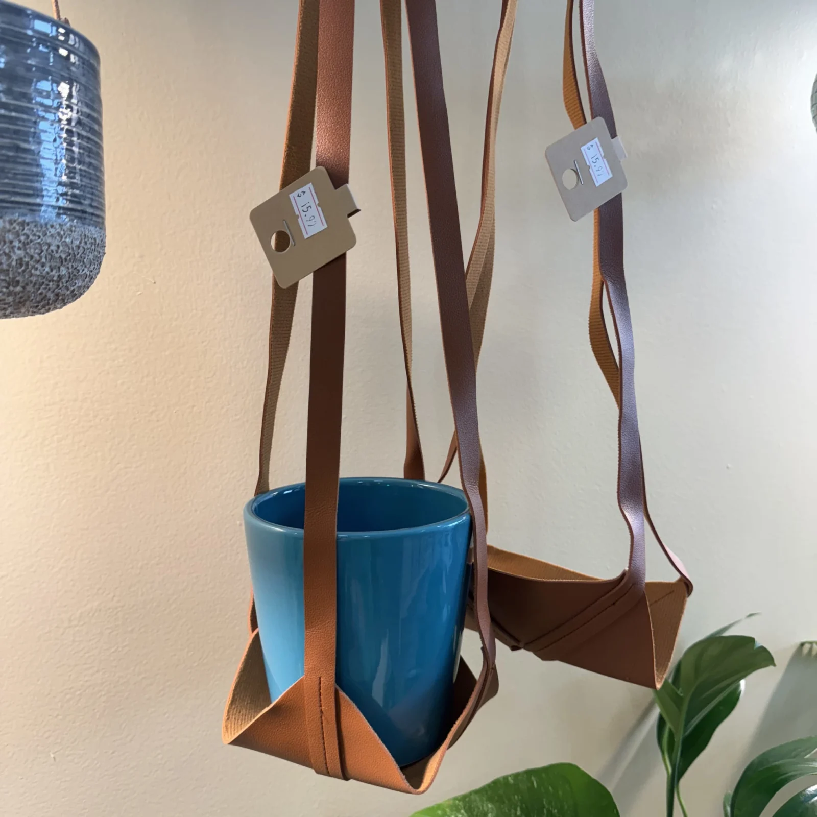 Leather Plant Hanger with blue ceramic pot suspended by brown leather straps.