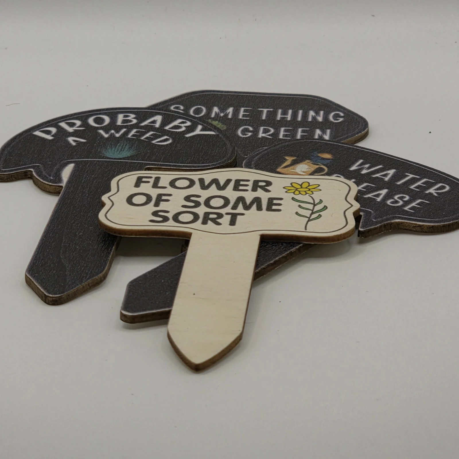Funny Plant Stakes with humorous text labels for garden plant identification and care.