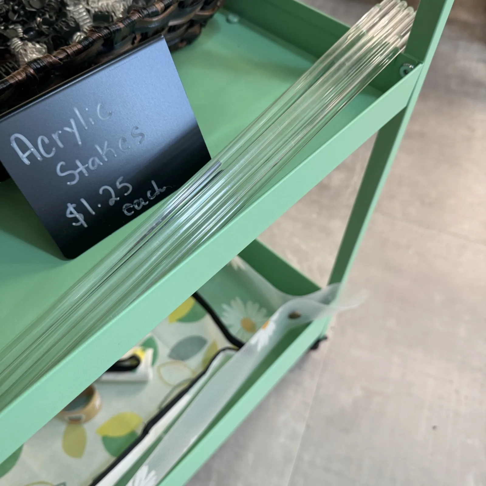Acrylic Stakes displayed on mint green shelf with price label and packaging below.