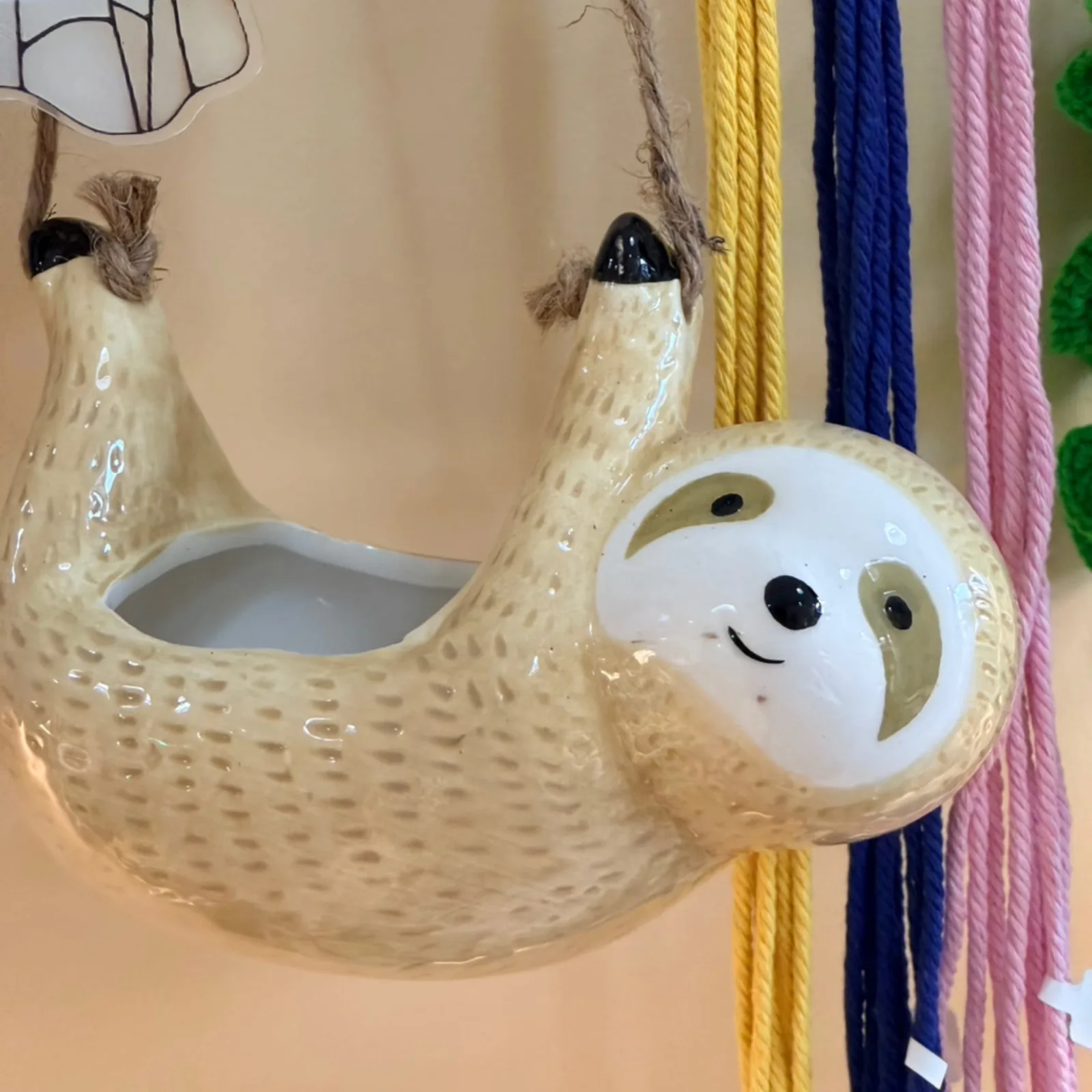 Sloth Hanging Pot with cream ceramic body, smiling face, and textured surface design.